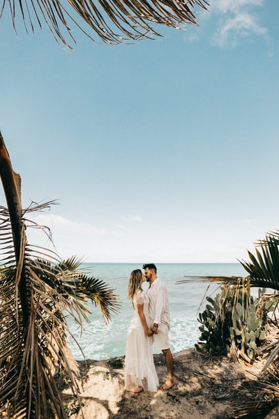 A man and a woman standing near the coconut trees
